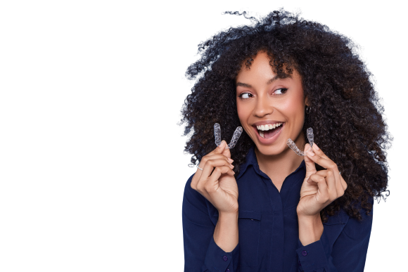Woman smiling while holding invisible aligner tray for orthodontic treatment