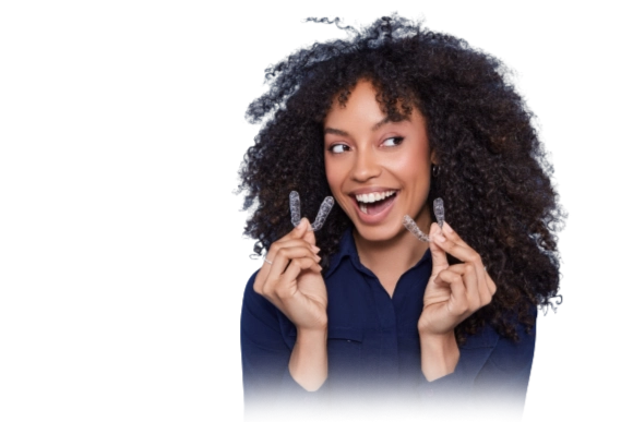 Woman smiling while holding invisible aligner tray for orthodontic treatment